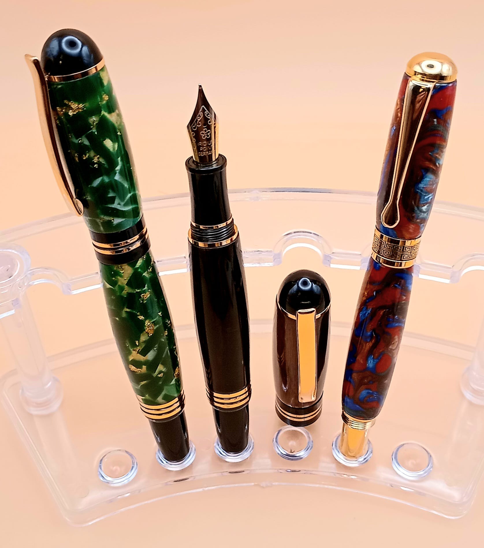 Emerald gold-fleck, polished black, and red-blue marbled fountain pens with gold accents