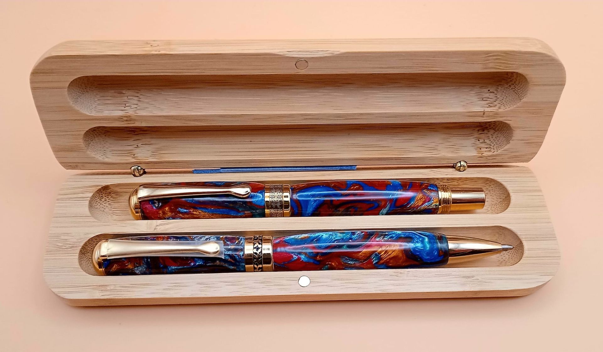 Matching pair of red and blue swirl resin pens in a handcrafted bamboo gift box