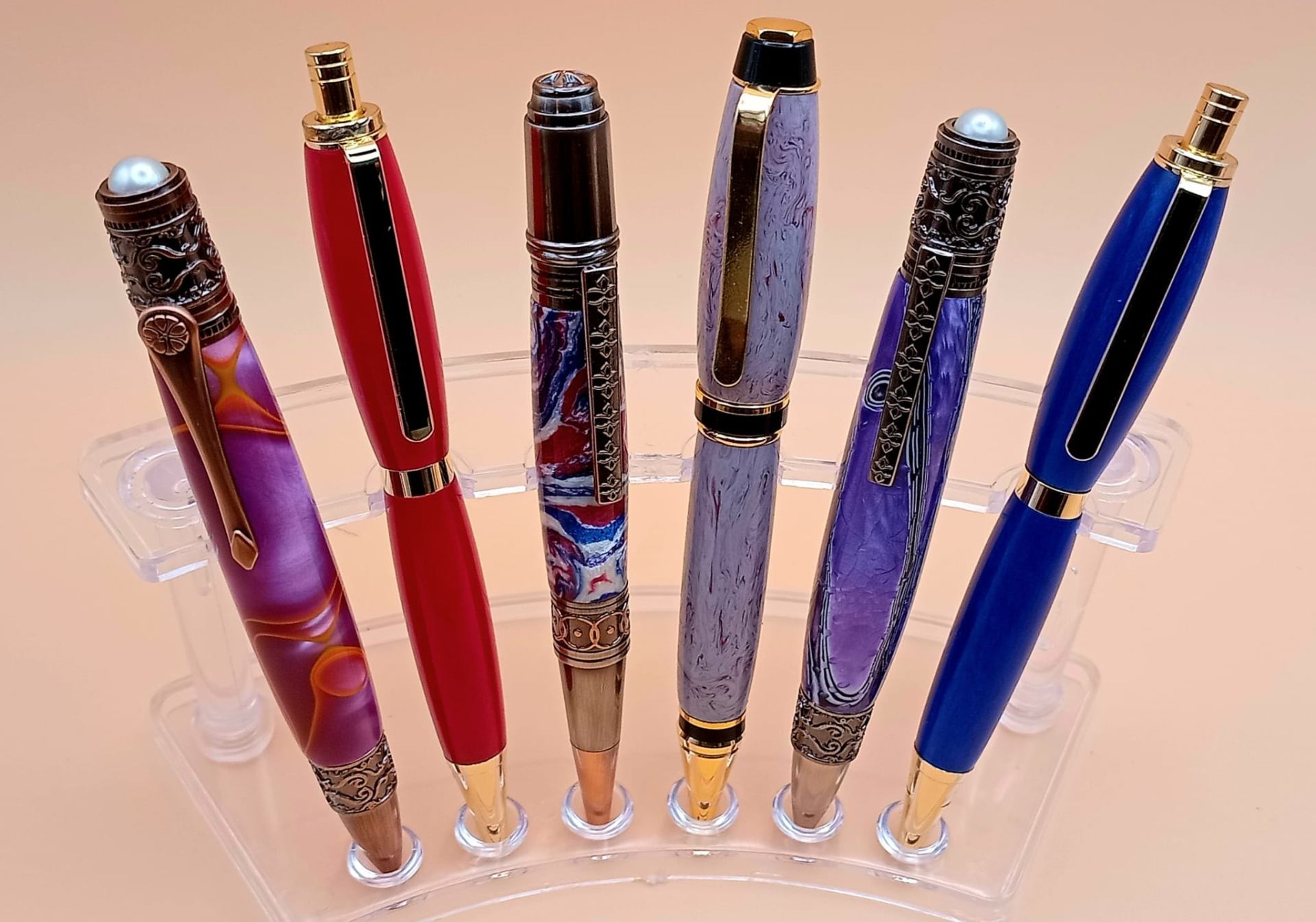 Resin pens with decorative filigree caps, pearl accents, and rich red, purple and blue bodies